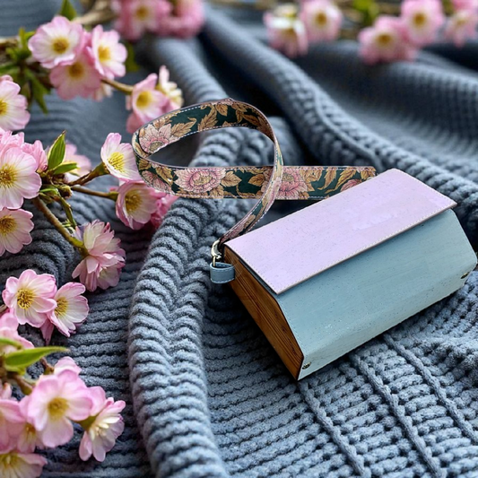 Small handbag with floral strap on a textured surface with cherry blossoms